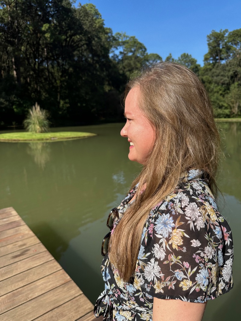 Annelie in profile by a still lake, smiling, in a flowered dress