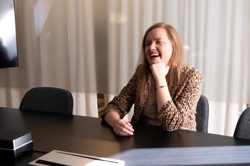 Annelie Näs laughing at a meeting table, wearing a leopard-print jacket
