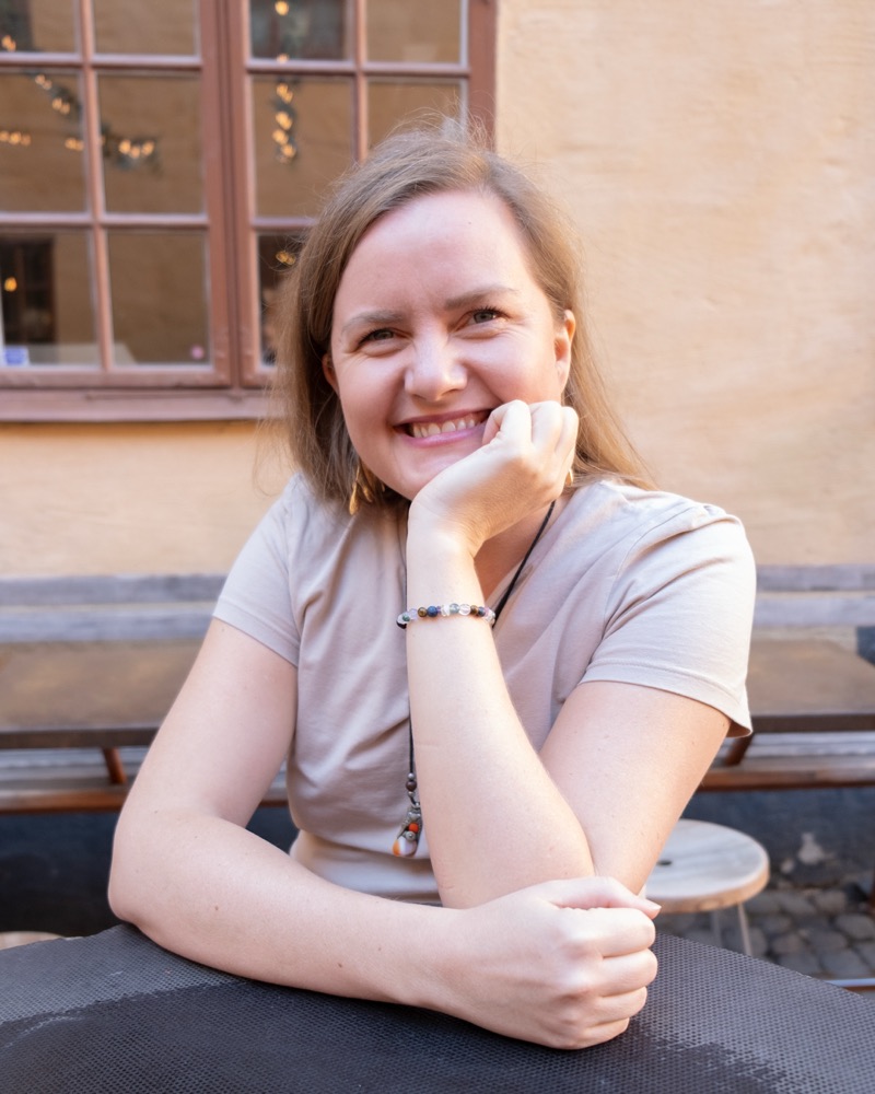 Annelie Näs resting her chin on her hand at an outdoor café table, smiling