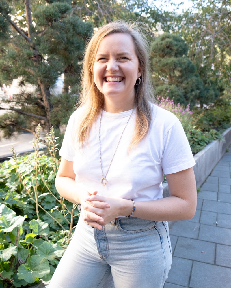 Annelie Näs laughing, standing in a garden in a white t-shirt