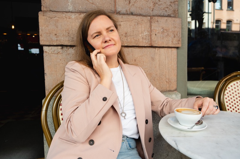 Annelie at a café table in Stockholm, on the phone, with a coffee in front of her