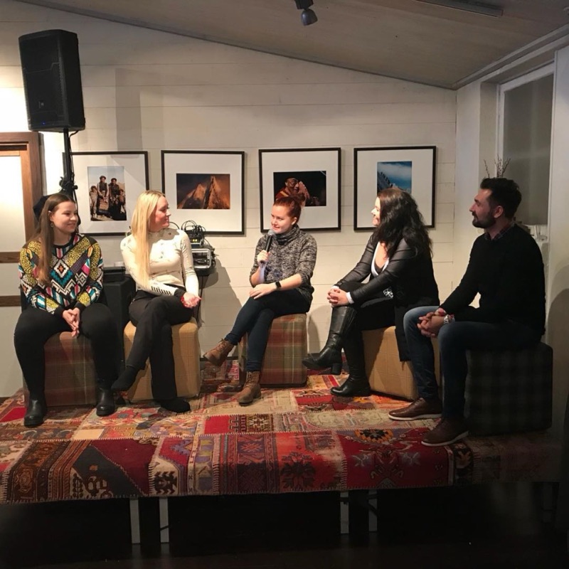 Annelie holding a microphone in the middle of a panel of five on a small stage